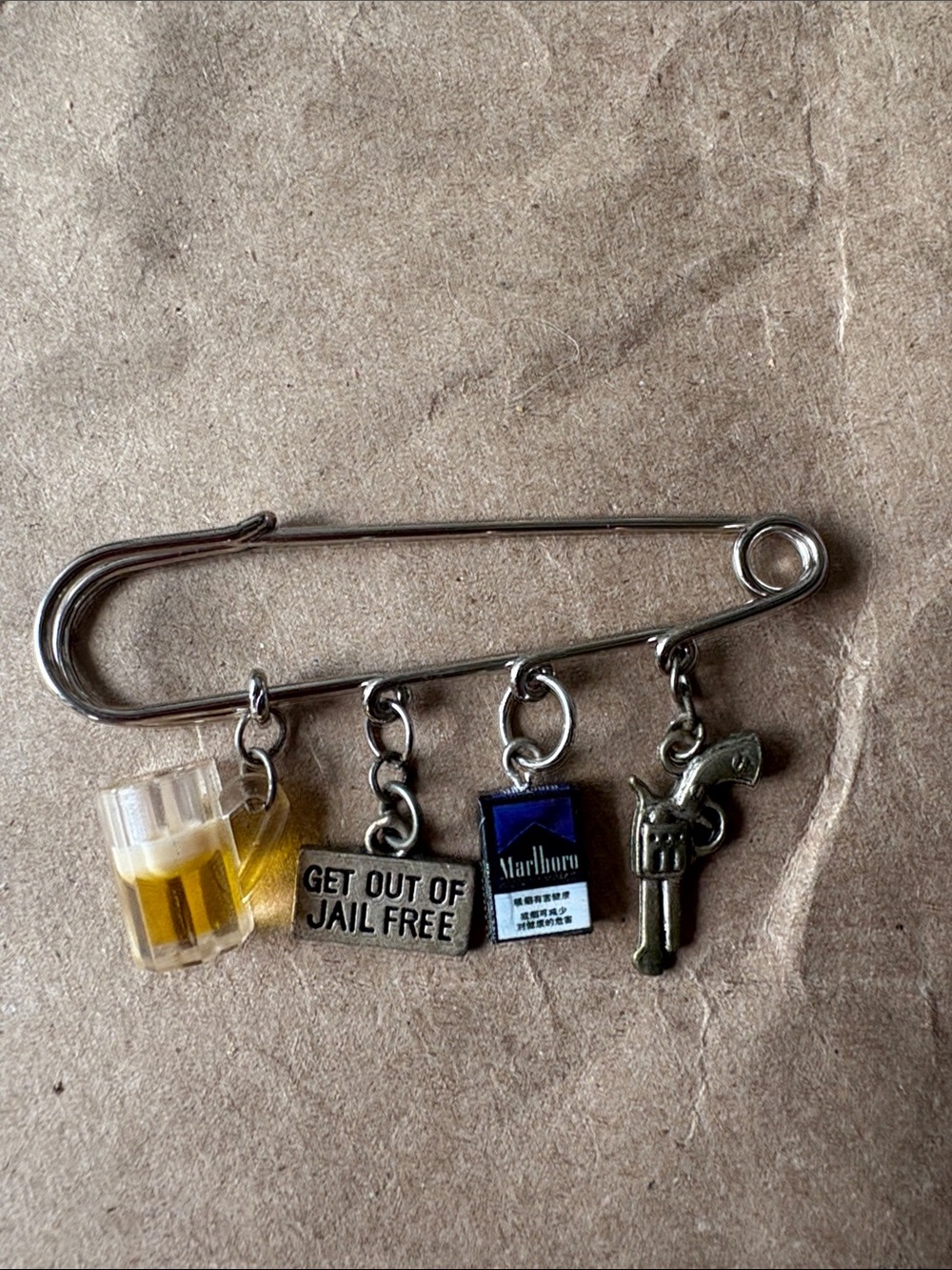 Silver Safety Pin Charm Brooch with Beer, Novelty Tag, Blue Pack and Gun Charms